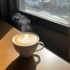 A cup of hot coffee on a table near a window enhanced by the gentle glow of the Soft Light Photoshop Action.